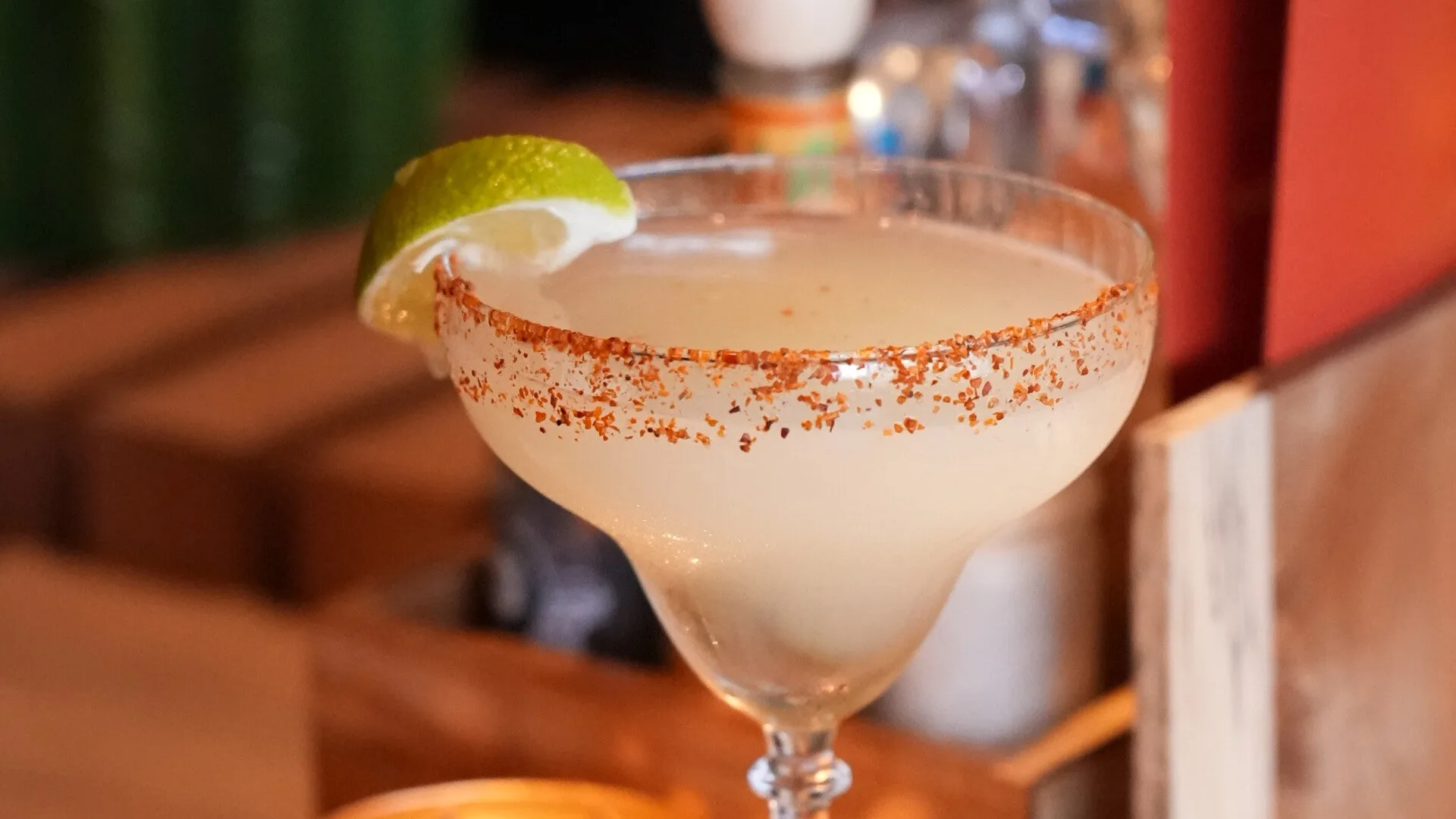 Een cocktail met chilirand en limoen op de bar van Cantina y Tacos, met de cactuswand op de achtergrond