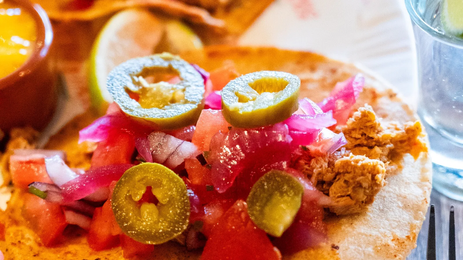 Soft tacos met pulled chicken, pico de gallo en jalapeno op een bord